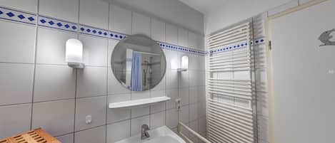 A bathroom with a sink, mirror, towel rack, and a shower area.