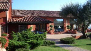 Un bâtiment doté d’un toit en tuiles, de grandes fenêtres et d’un espace extérieur aménagé pour s’asseoir.