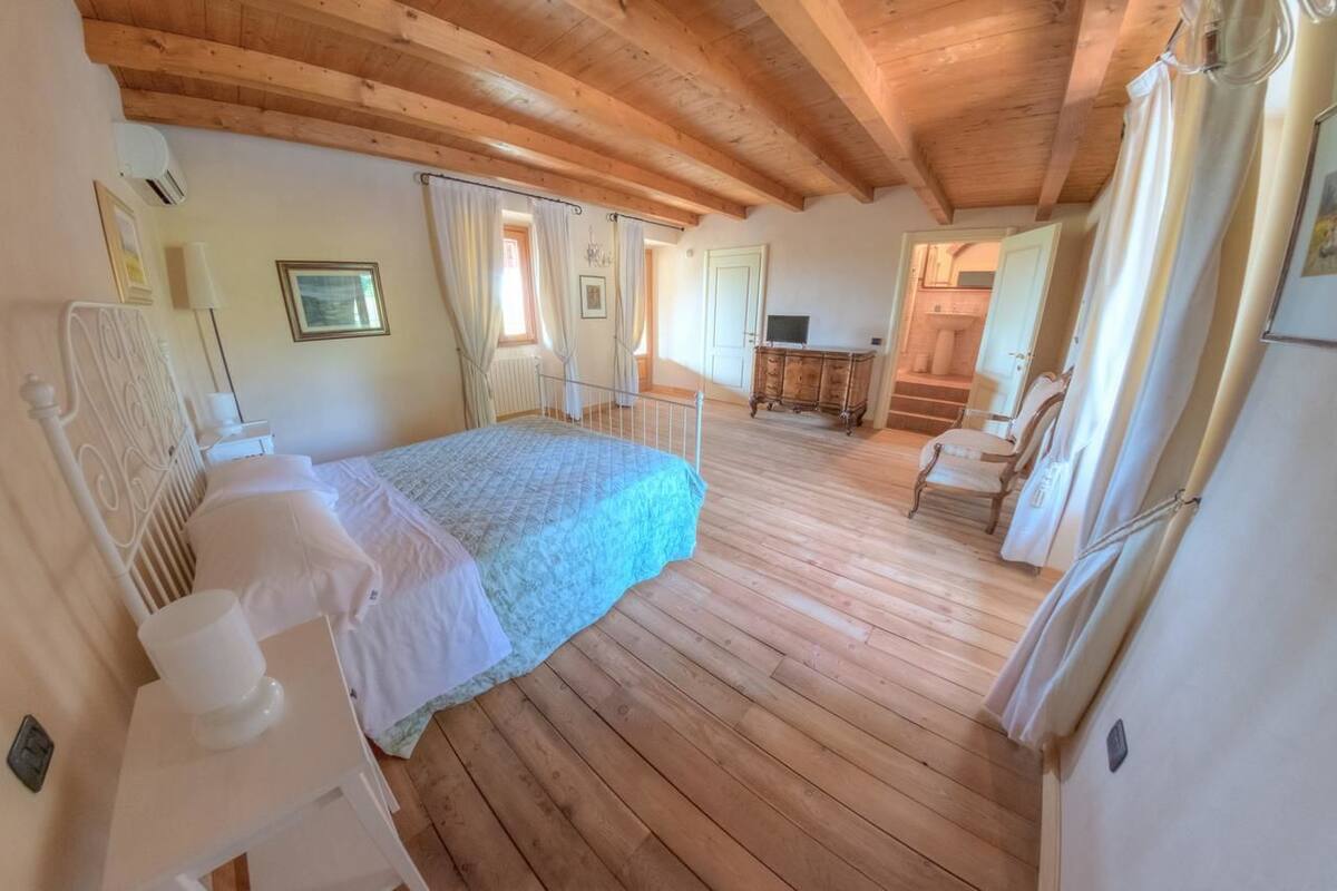 Ein Schlafzimmer mit Holzboden, einem Bett mit blauer Decke, einem weißen Nachttisch und einer Holzkommode.
