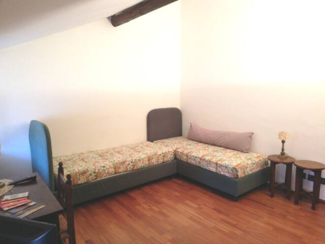 A small room with a single bed, a desk, and two small tables.