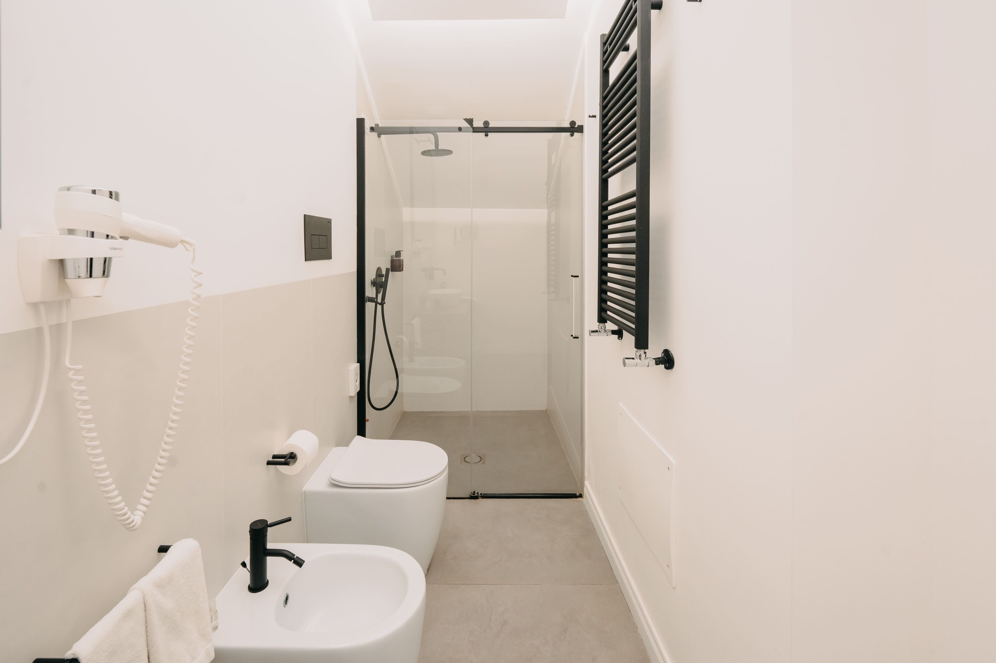 A compact bathroom with a toilet, sink, and shower.