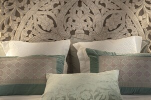 A bed with a decorative headboard and multiple pillows.
