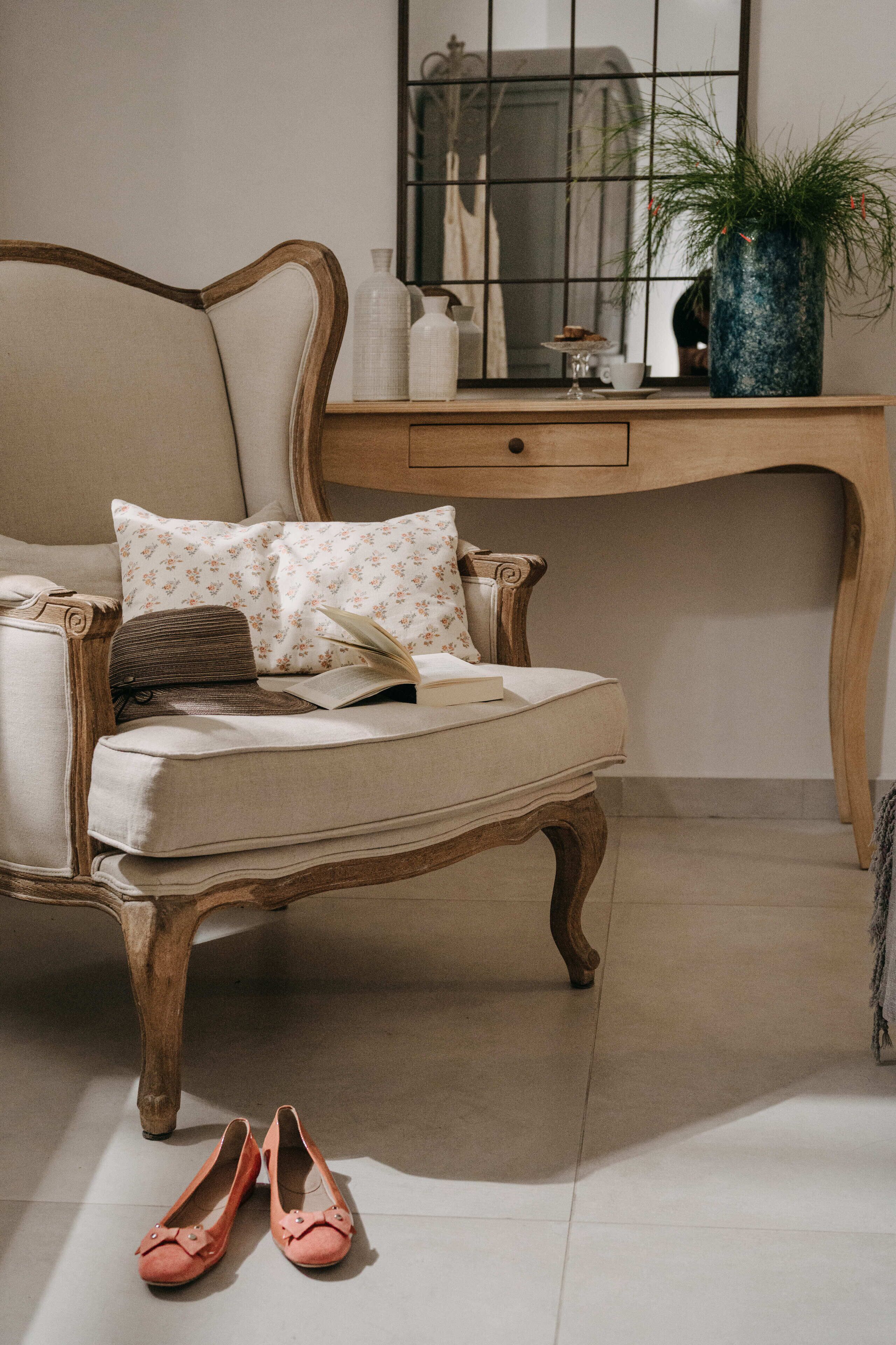 A chair with a cushion, a book, a pair of shoes, and a desk with a plant and decorative items.