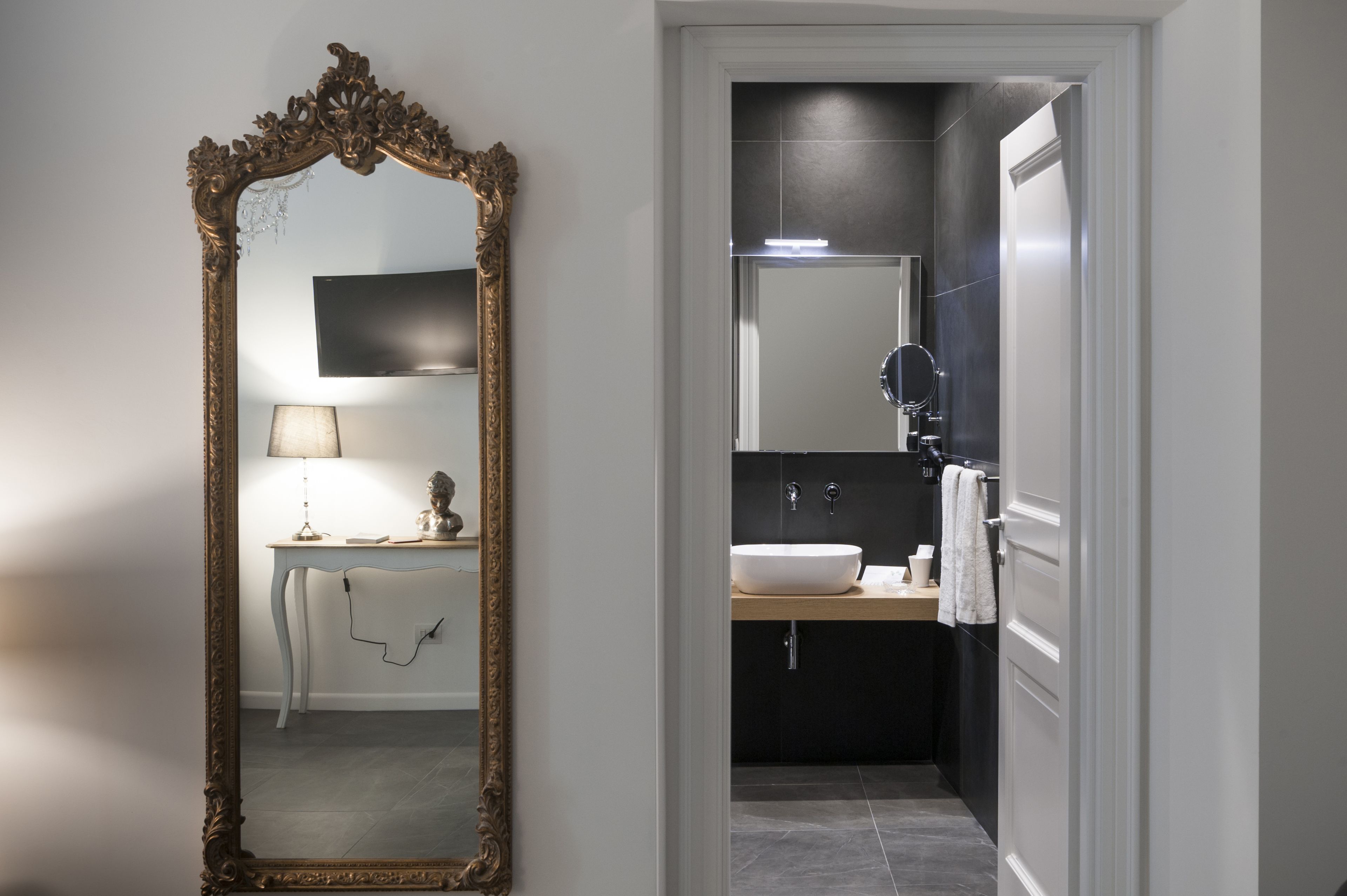 Un bagno con uno specchio grande e decorato, un lavabo e un mobile vanità con una lampada.