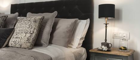 A neatly made bed with a tufted headboard, a bedside table with a lamp, and decorative items.