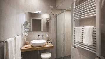Ein modernes Badezimmer mit großem Spiegel, Waschbecken, Toilette und Duschkabine aus Glas.