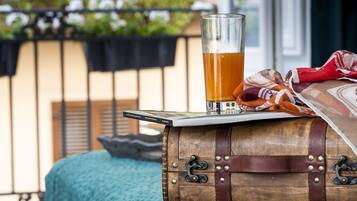 A glass of beer on a wooden barrel, a book, and a colorful cloth on a balcony railing.