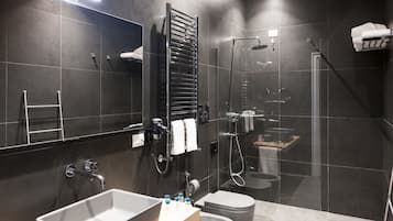 A modern bathroom with a large mirror, a towel rack, a shower, a toilet, and a sink.