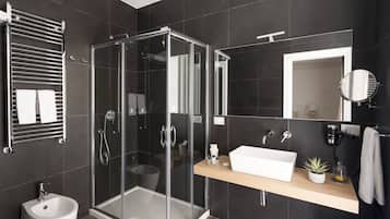 A modern bathroom with a glass-enclosed shower, a white sink, and a mirror.