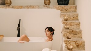 A bathroom with a bathtub, a stone staircase, and decorative baskets.