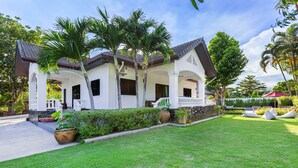 A two-story house with a covered porch, palm trees, and a well-maintained lawn. - Happy Family Villa 2  (Chalong)