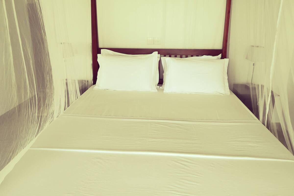 A bed with white linens and a wooden headboard.