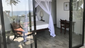 A bedroom with a bed, a chair, and a nightstand. - Lara's Place Unawatuna (Unawatuna)