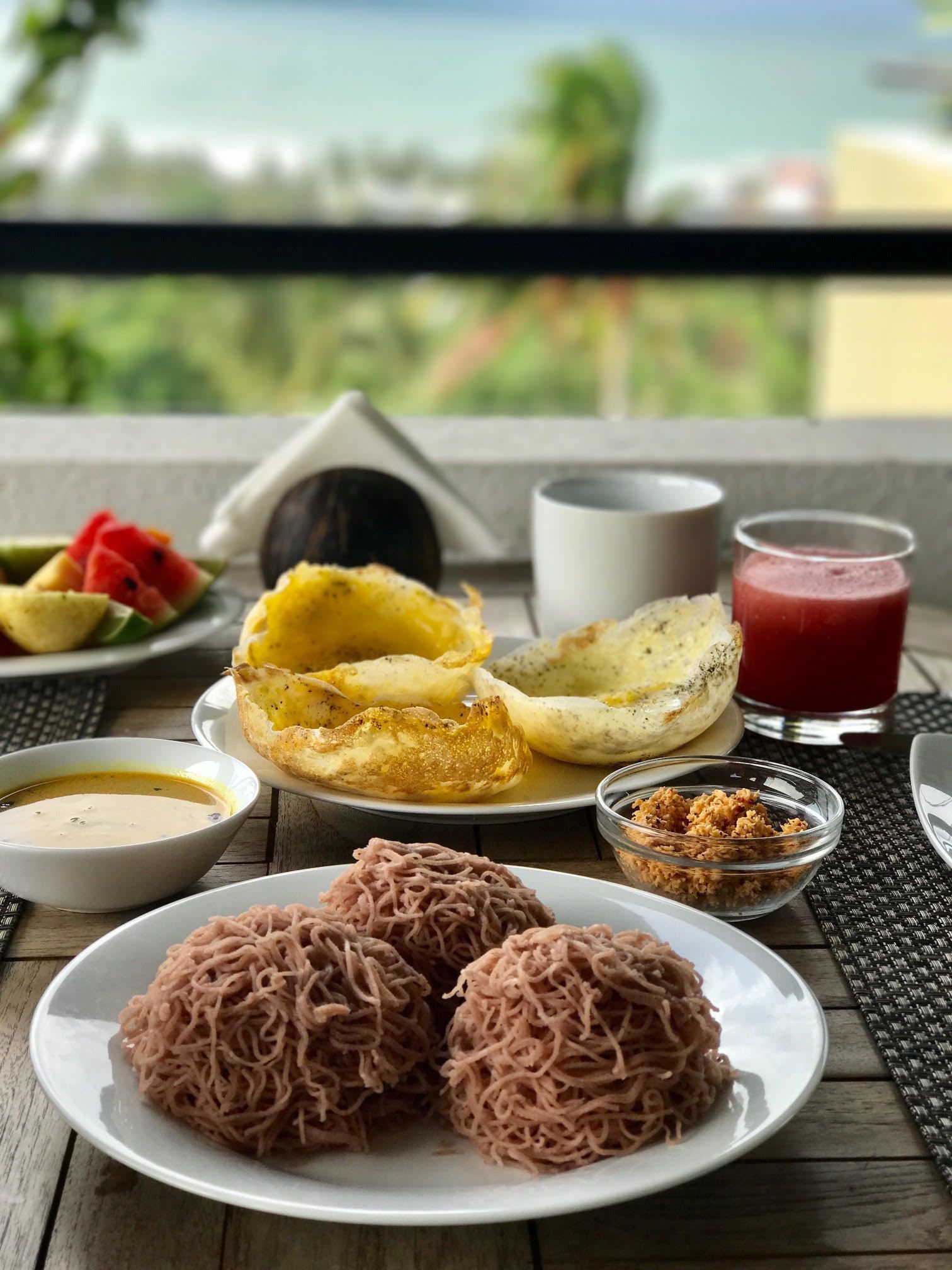 A table with food items including noodles, a bowl of soup, and a fruit plate.