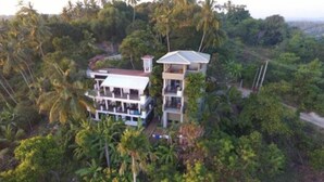 A two-story building with multiple balconies, surrounded by dense tropical vegetation. - Lara's Place Unawatuna (Unawatuna)