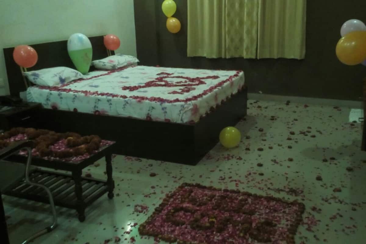 Une pièce avec un lit, des ballons et des pétales de rose éparpillés sur le sol.