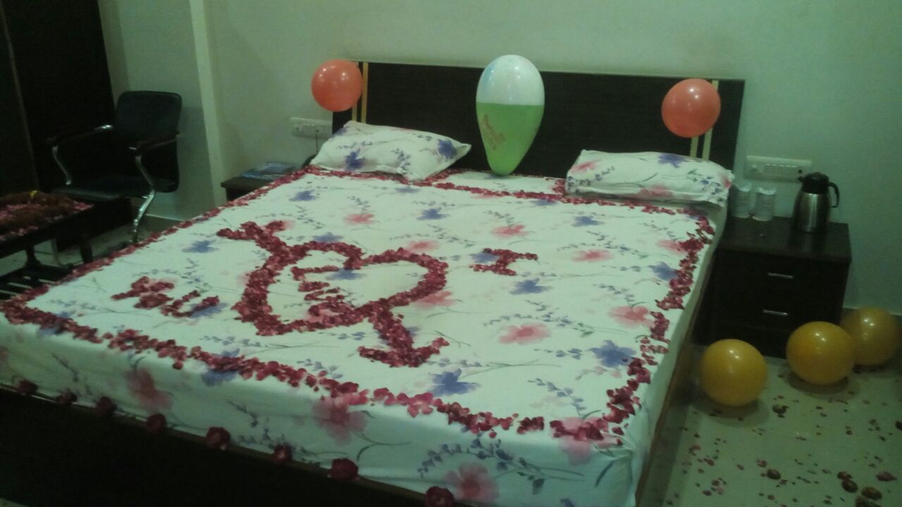A bed with a floral bedspread, heart-shaped decorations, and balloons.