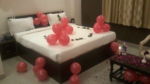 Una habitación de hotel con una cama, almohadas y globos dispersos.