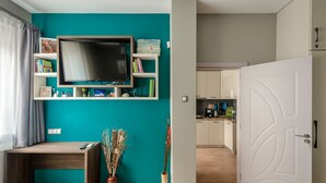 Ein modernes Wohnzimmer mit einer türkisblauen Akzentwand, einem Flachbildfernseher, einem Holztisch und einem Blumentopf.