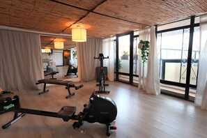 A gym with exercise equipment, large windows, and a wooden ceiling.