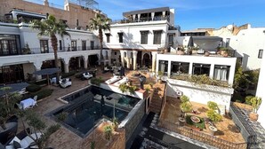 Ein Innenhof mit Schwimmbad, Sitzgelegenheiten im Freien und einer Treppe zu einer Dachterrasse.