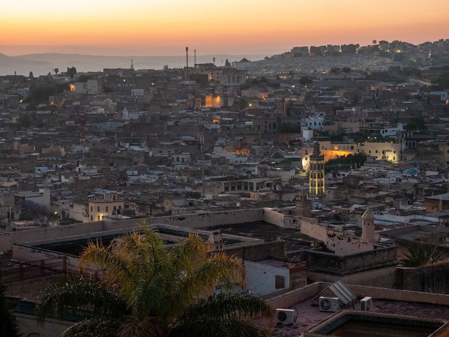 A densely packed urban area with a prominent tower and a mosque with a minaret, surrounded by residential buildings.