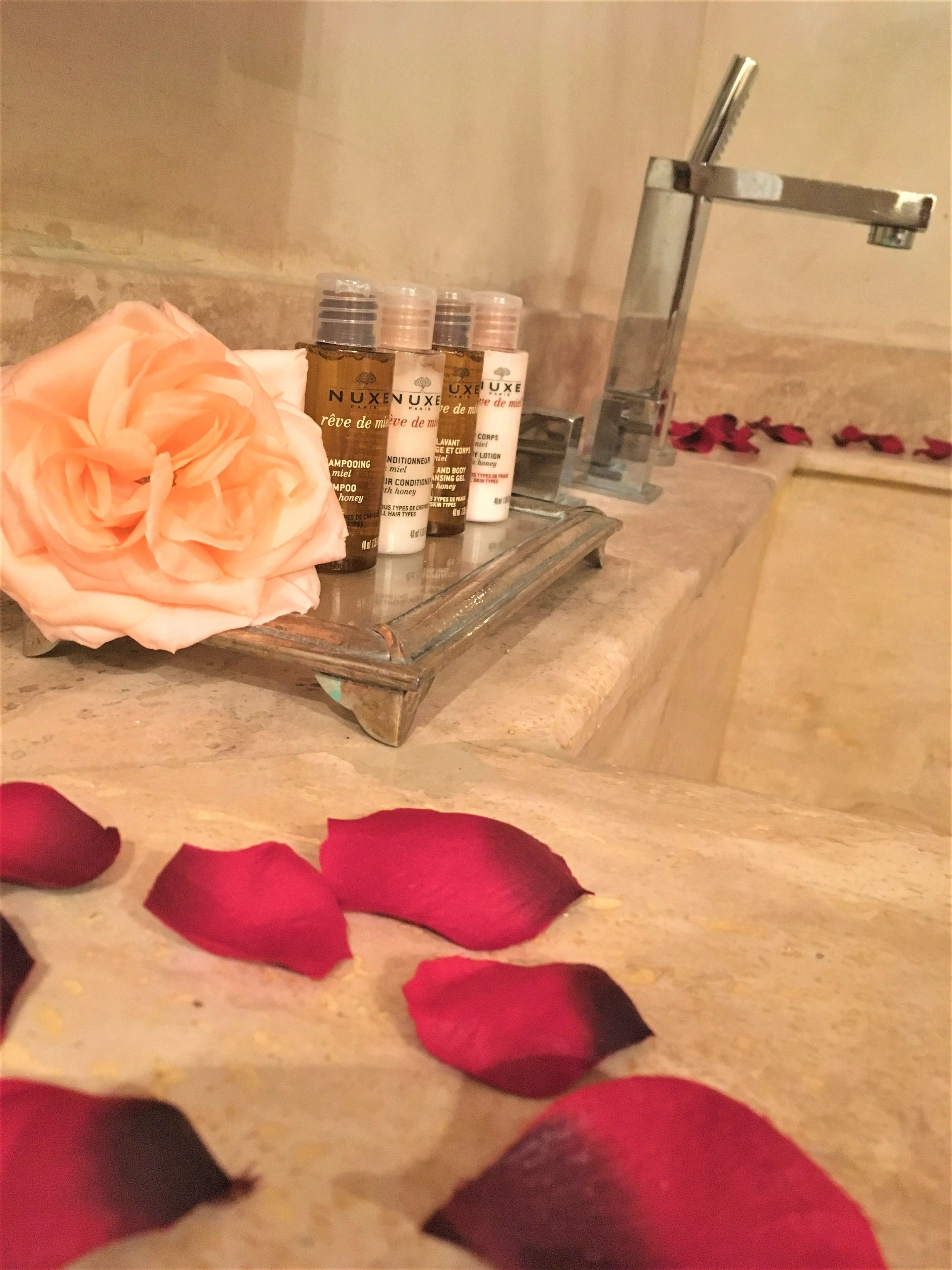 Un tocador de baño con artículos de aseo y pétalos de rosa.