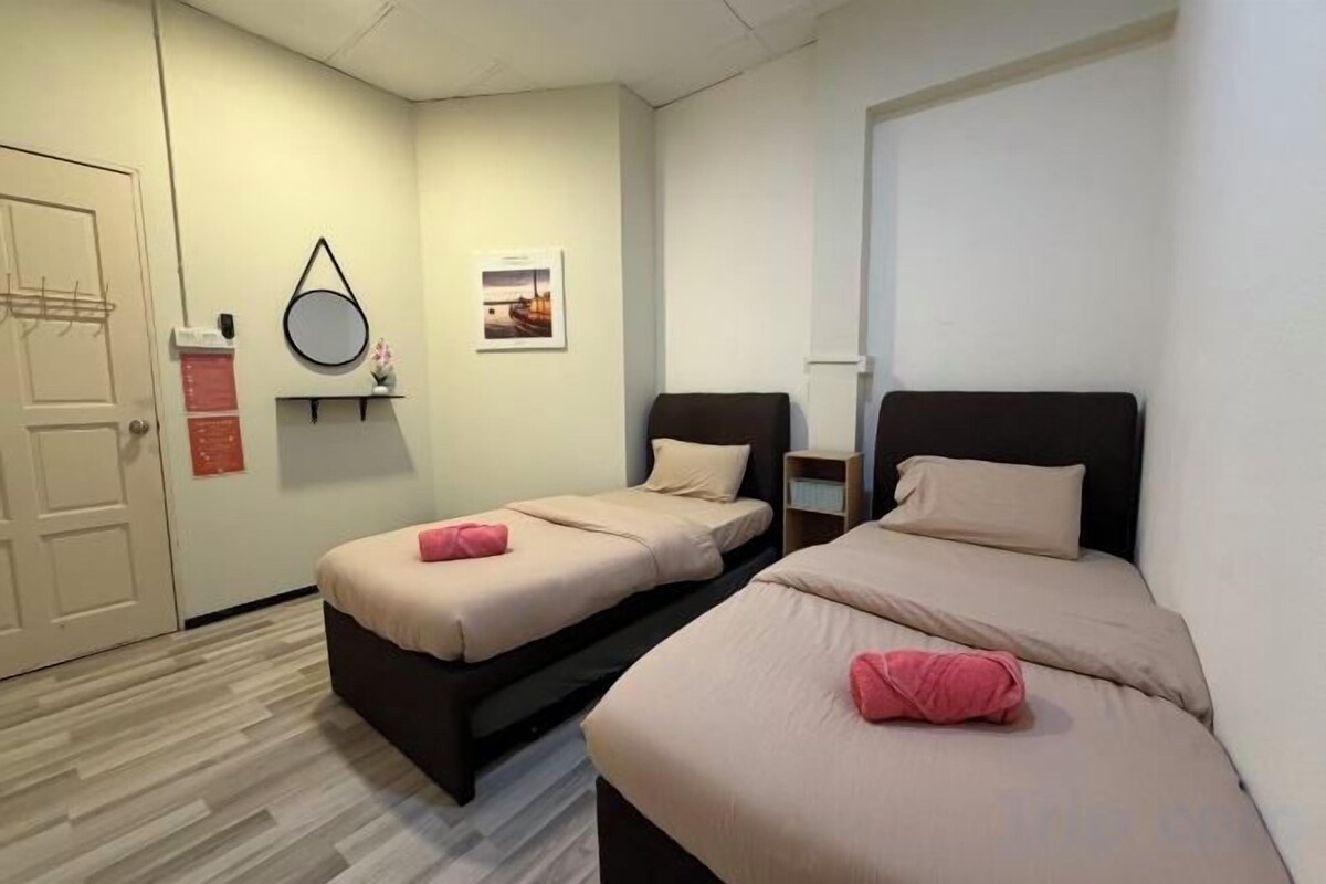 A bedroom with two beds, a door, a mirror, and a small table.