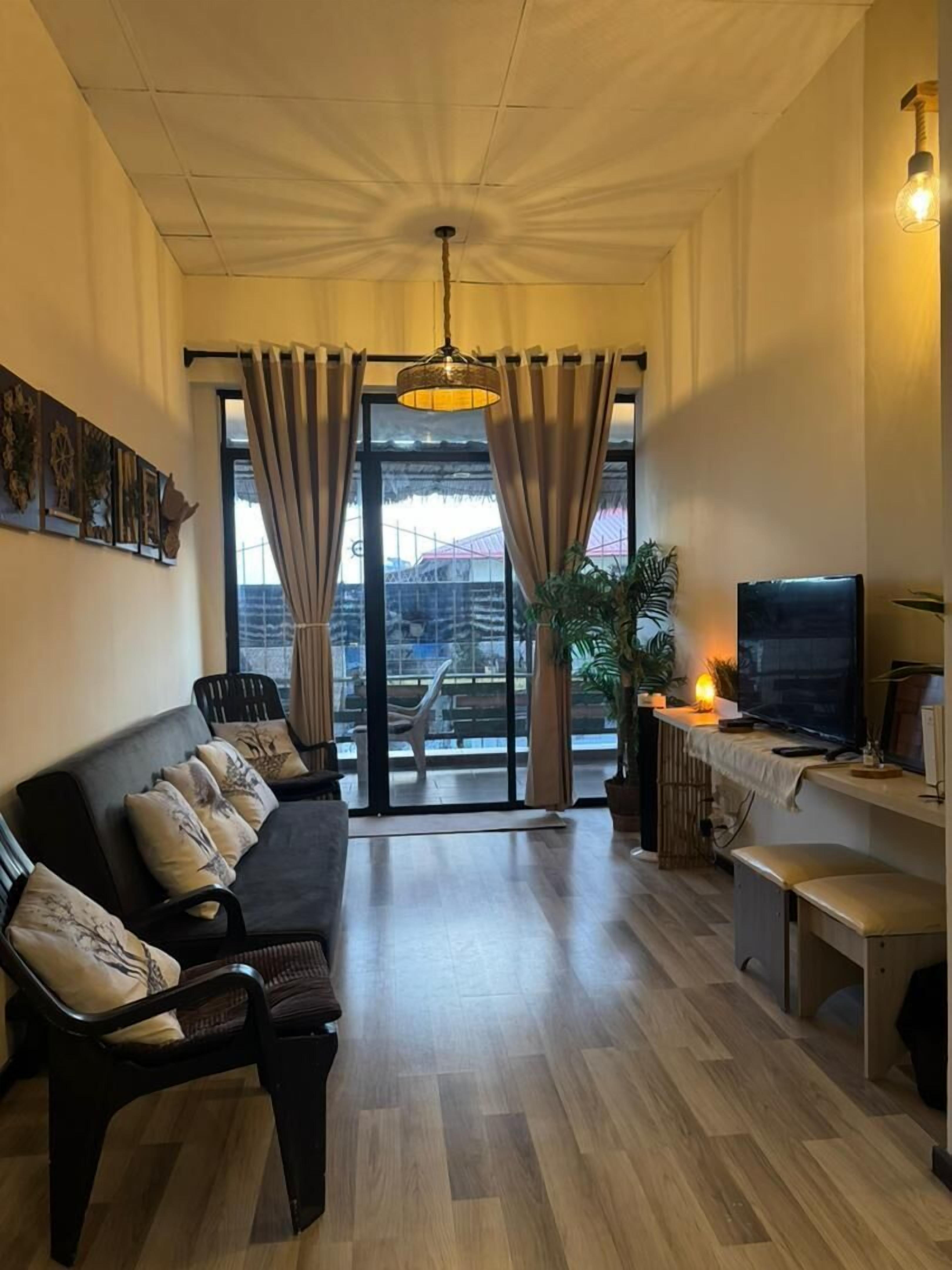 A modern living room with a sofa, TV, and a balcony view.