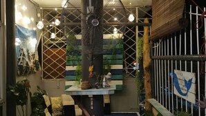 A cozy indoor space with a large fan, seating area, and potted plants. - The Village (Semporna)