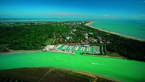 An aerial view of a coastal area with a marina, green spaces, and a beach. - Lignano Riviera Spacious (Lignano Sabbiadoro)