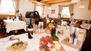 A restaurant with multiple tables set for dining, featuring a variety of dishes, wine, and bread.