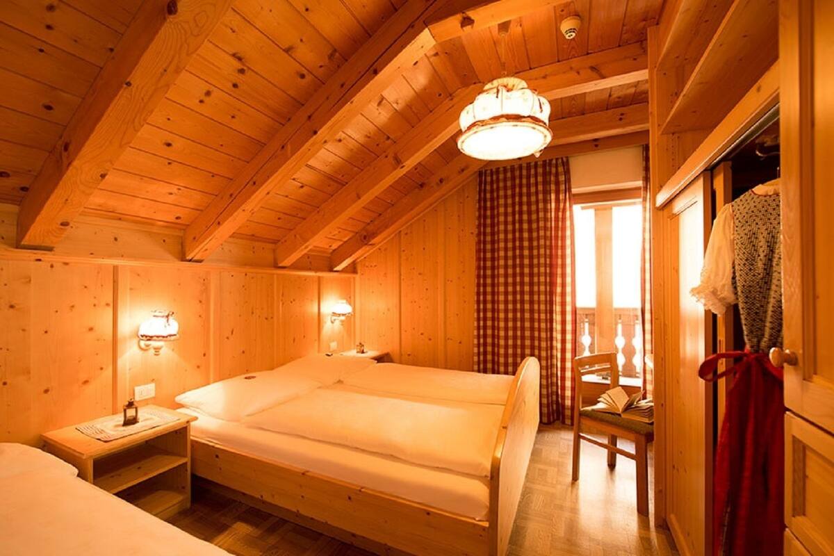 Une chambre dans une cabane en bois, avec un grand lit, deux tables de chevet et une fenêtre avec des rideaux.
