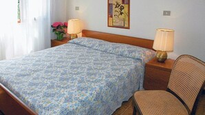 A hotel room with a bed, two bedside lamps, a chair, and a wall decoration. - Lignano with pool (Lignano Sabbiadoro)