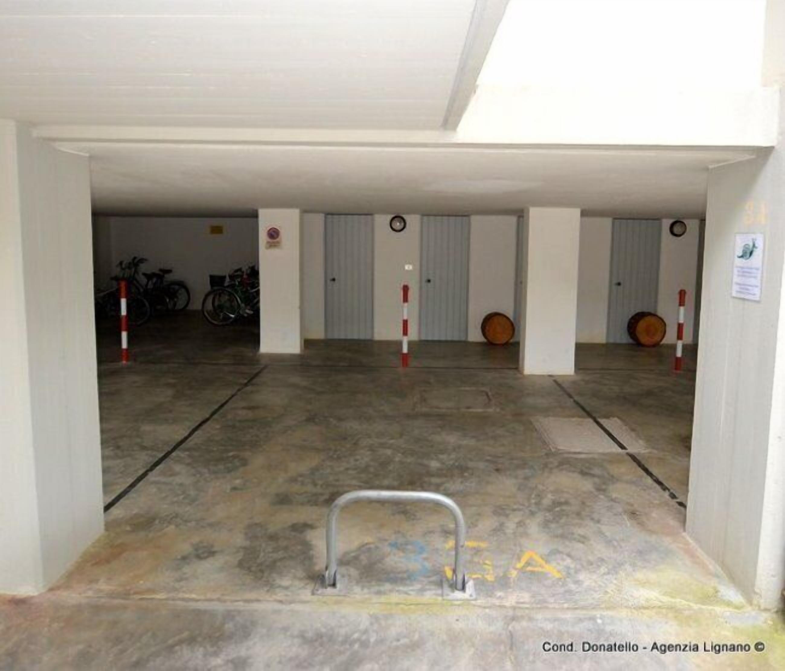 A parking garage with concrete floors, metal bollards, and bicycles parked against the walls.