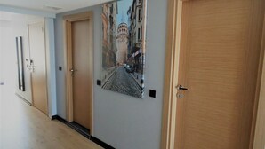 A hallway with wooden doors, a tiled floor, and a wall-mounted picture of a street scene. - VVR Hotel (Istanbul)