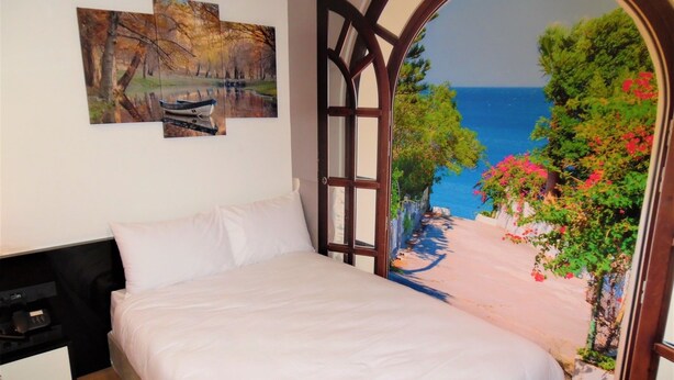 A bedroom with a bed, a nightstand, and a wall with three paintings. - VVR Hotel (Istanbul)