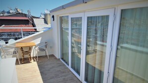 A balcony with a table and chairs, a sliding glass door, and a view of the cityscape. - VVR Hotel (Istanbul)