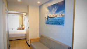 A hotel room with a bed, a sofa, a painting of a cityscape, and a wooden floor. - VVR Hotel (Istanbul)