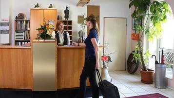 Un comptoir d’accueil avec un revêtement en bois, une plante en pot et une grande fenêtre donnant sur l’extérieur.