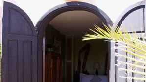 An open doorway leading to a bedroom with a bed, a patterned rug, and a hanging lamp. - Riad Dama (Marrakech)