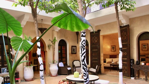A courtyard with a round table, chairs, and potted plants. - Riad Dama (Marrakech)