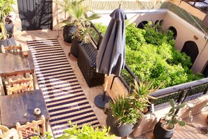 A rooftop garden with potted plants, a striped rug, and outdoor furniture. - Riad Dama (Marrakech)