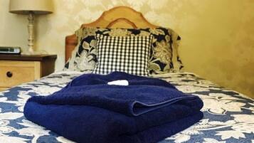 A neatly made bed with a blue blanket and a floral-patterned bedspread.