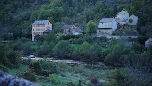 A hotel with multiple buildings on a hillside, surrounded by dense greenery and a river.