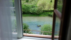 A view of a river from a window, with a person swimming in the water.