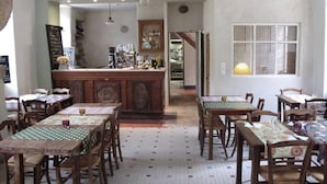 A cozy restaurant with wooden tables and chairs, a bar area, and a tiled floor.