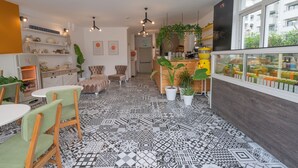 A modern cafe with patterned floor tiles, wooden furniture, and a variety of plants. - Muse No:1 (Marmaris)