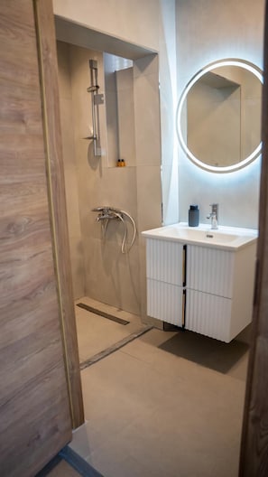 Ein modernes Badezimmer mit begehbarer Dusche, Waschtisch und Spiegel sowie Toilette.