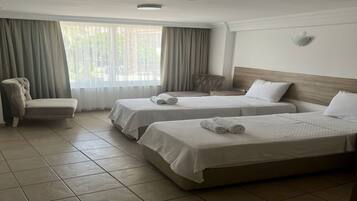 Habitación de hotel con dos camas, una silla y una ventana con cortinas.